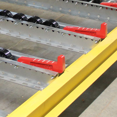 Pallet flow lanes with plastic wheels have integrated metal pallet stops to keep pallets inside the bay.